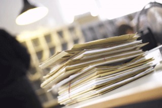 Full-Service Leistung ProMediaService Gmbh - Abb. Schreibtisch mit Papierstapel im Vordergrund