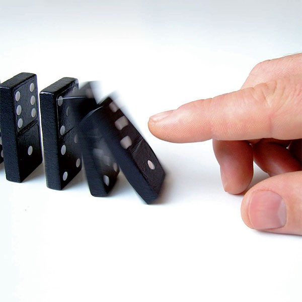 Projektmanagement - Qualitätsmanagement ProMediaService GmbH - Abb. Großaufnahme von Dominosteinen die von einem Finger angestoßen werden.